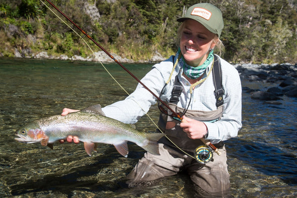 Woman holding a large trout while fly fishing in a New Zealand river