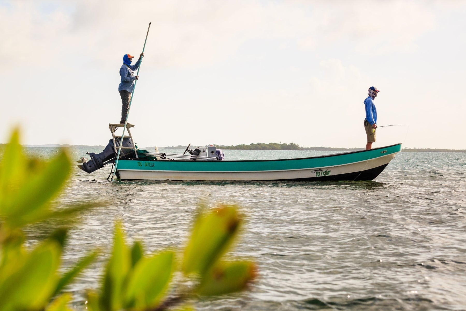 Two anglers fly fish from a boat on coastal waters