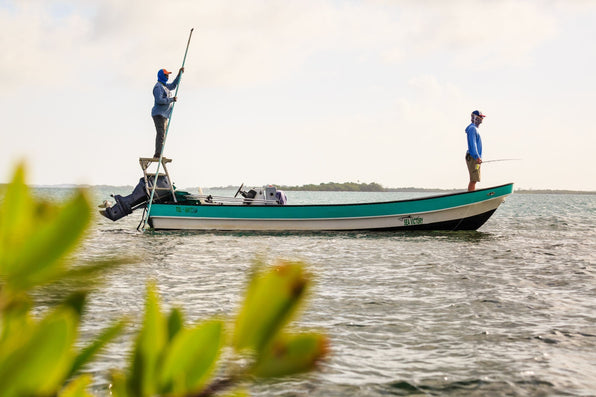 Two anglers fly fish from a boat on coastal waters