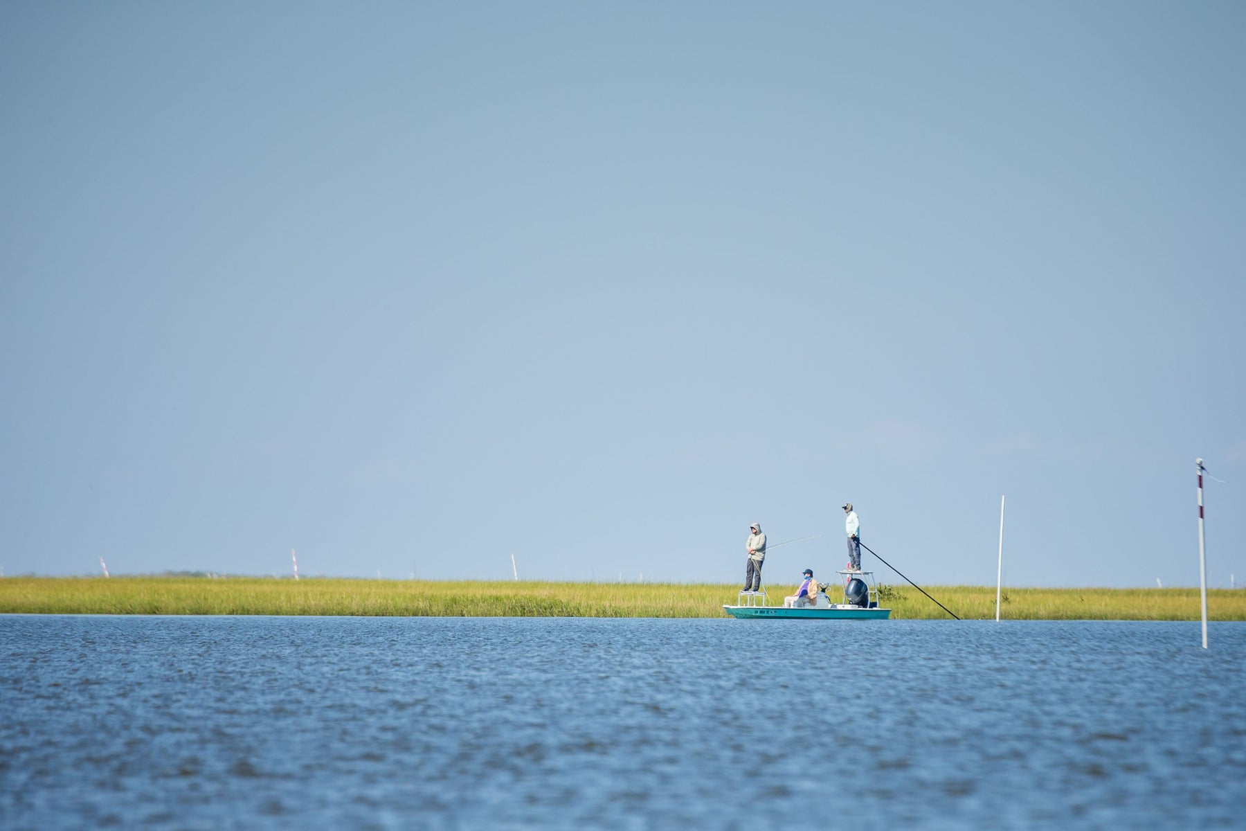 Fly fishers fish from a flats boat on Louisiana marsh waters