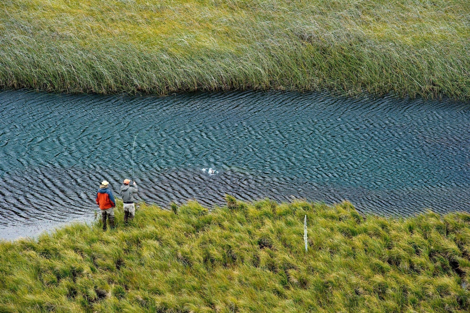 Two anglers fly fishing beside a wind-rippled lake in Chilean Patagonia
