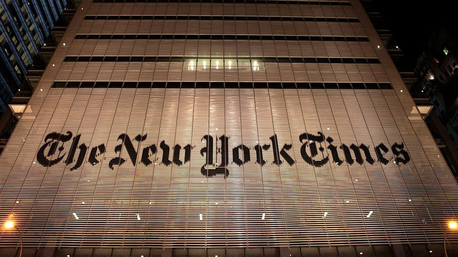 Night view of The New York Times building facade displaying the large 'The New York Times' sign