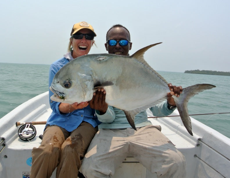 Angler and guide holding a large permit in Punta Gorda, Belize on a fly fishing trip, caught on a floating crab dry fly
