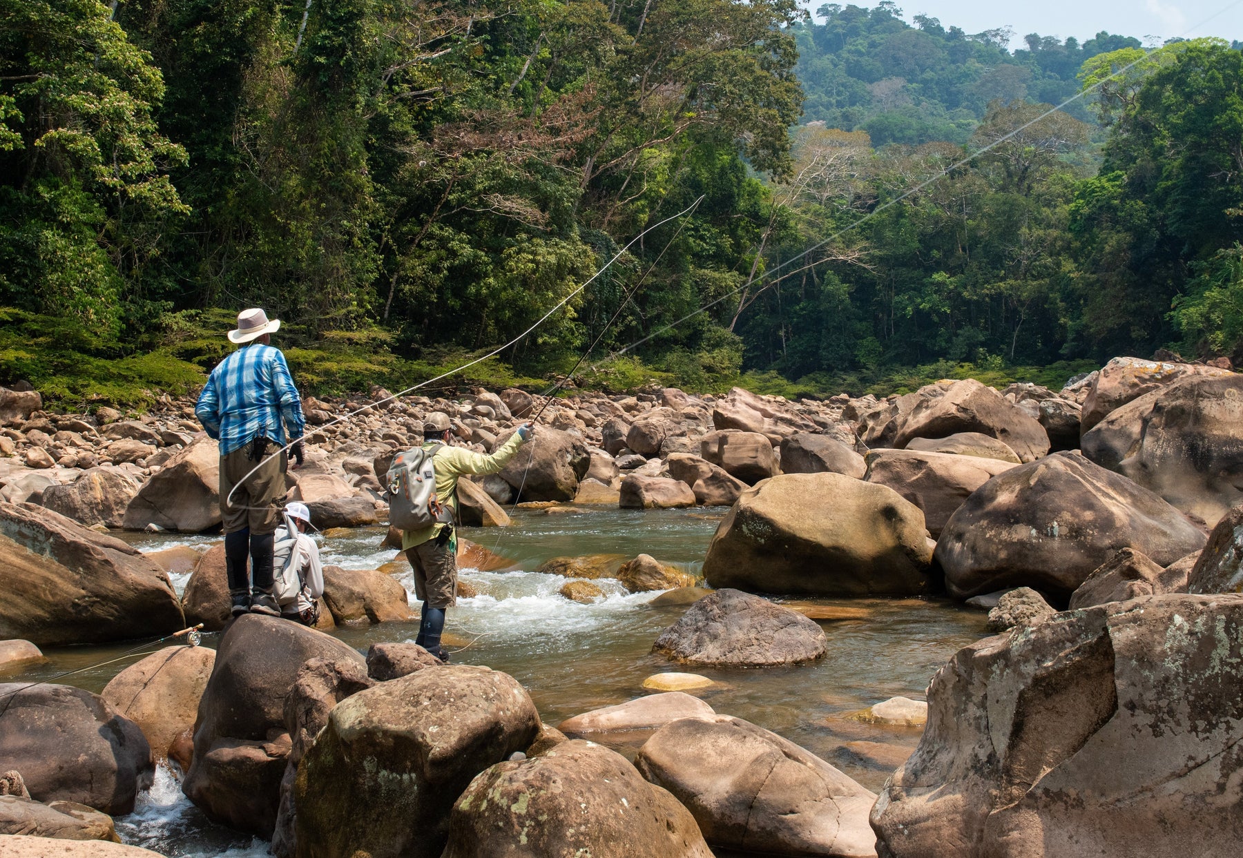 yellow-dog-flyfish Three anglers fly fishing on a rocky Bolivian river with rainforest-covered hills in the background