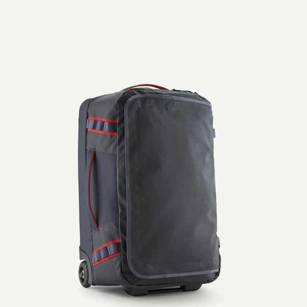 Three-quarter view of Patagonia Black Hole Wheeled Duffel 40L with front zip pocket, red trim and wheels on light background
