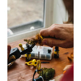 Hand using Loon Outdoors Ergo Hair Packer to compress deer hair on a fly in a vise on a wooden workbench