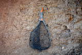 Front view of Fishpond Nomad Yampa hand net showcasing camo composite handle and black rubber hex net against a rocky background