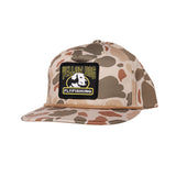 A flat-brim snapback cap in a desert camouflage pattern, featuring a black rectangular patch on the front with the text 'YELLOW DOG FLYFISHING' and a dog graphic.